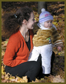 A woman and child sitting in the leaves.